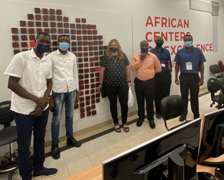 5 men and 1 woman standing in front of African Centers of Excellence