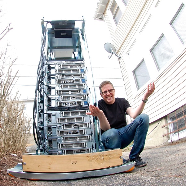 Chris Dagdigian crouched next to a server rack