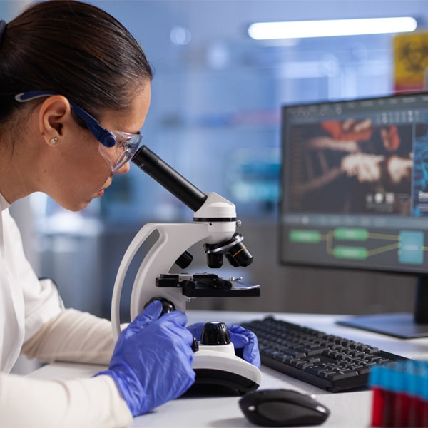 Microbiologist doctor analyzing dna sample using medical microscope during clinical experiment in hospital laboratory.